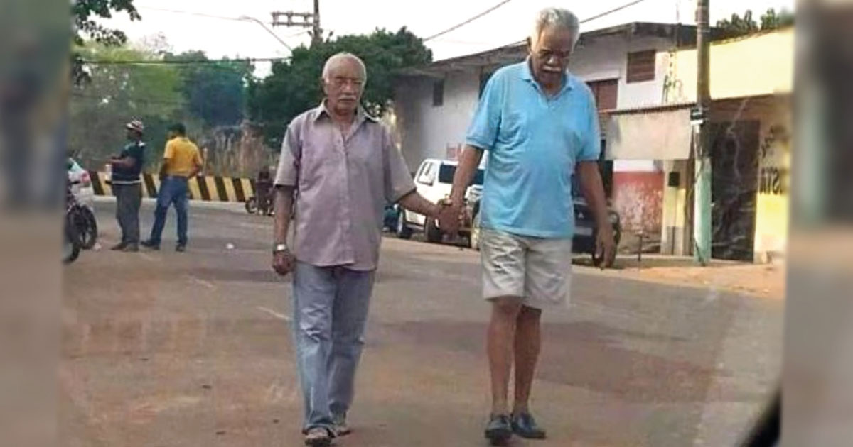 Viejo amigo lo ayuda a caminar de la mano porque no puede ver. Amistad verdadera